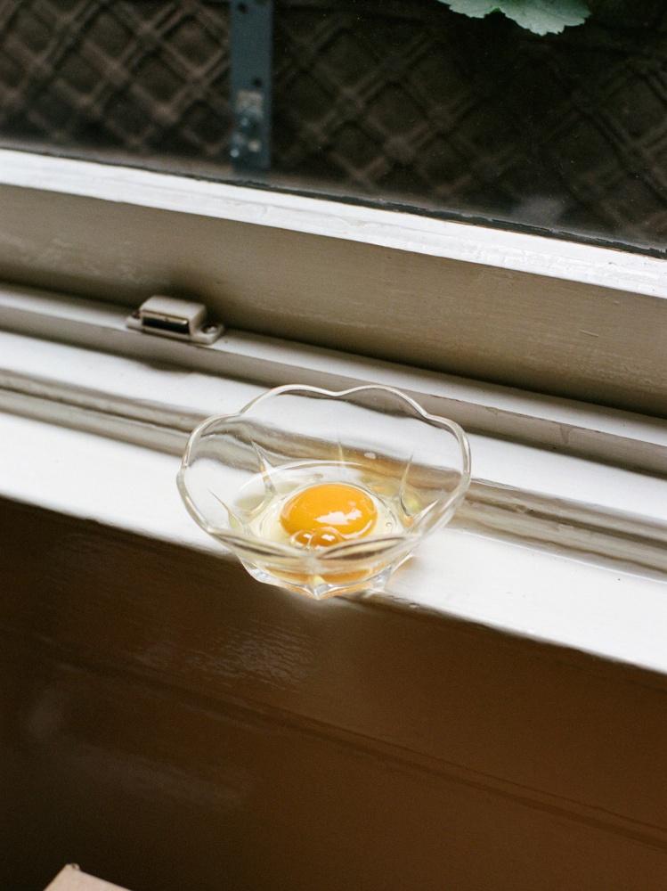 One raw egg in a glass bowl